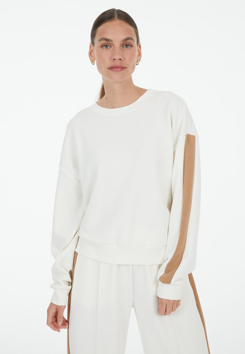 White sweatshirt with long sleeves, featuring a brown stripe along the sleeves. Smooth texture, round neckline, relaxed fit at the hem.