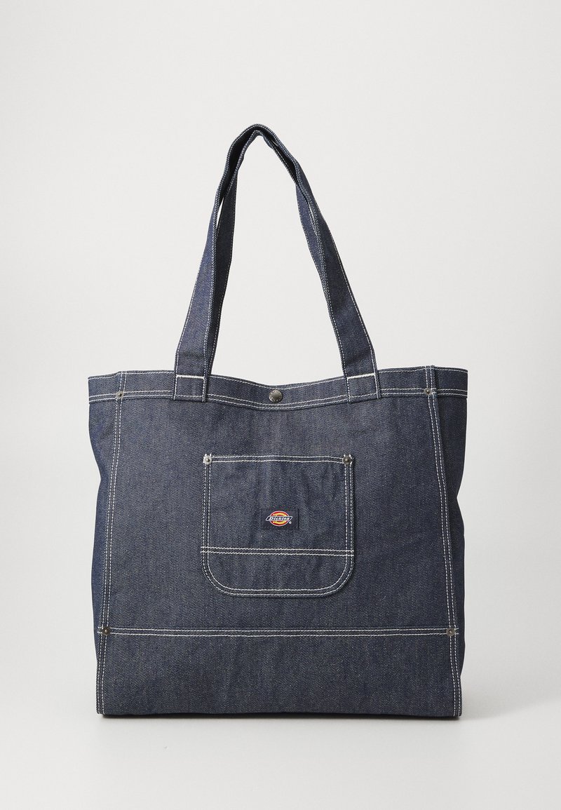 Jeanslixtotebag med två kraftiga handtag, mörkblå färg, vit sömnad, en framficka och ett litet logopatch nära toppen.