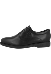 Scarpa da uomo in pelle nera con finitura liscia, punta arrotondata, design con lacci e suola bassa in gomma testurizzata. Include un sottile dettaglio laterale.