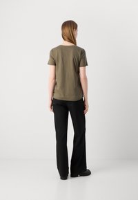 Olijfgroene t-shirt met korte mouwen en een ronde hals, van zachte stof met een losse pasvorm, gecombineerd met zwarte brede broek.