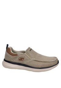 Scarpe beige slip-on in materiale canvas, con una finitura testurizzata, dettagli marroni e una suola in gomma bianca. Presentano un logo sul lato esterno.