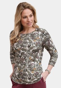 Blumenmuster-Oberteil mit langen Ärmeln in Creme, das grüne, lila und orangefarbene Muster aufweist. Weicher Stoff mit rundem Kragen und Dreiviertelärmeln.