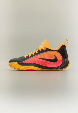 Chaussure de sport basse avec un design en dégradé noir, orange et rose, des lacets jaunes et le logo Nike noir sur le côté.