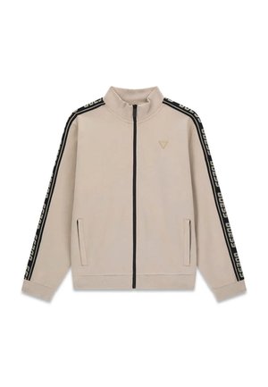 Veste beige zippée avec col haut, rayures noires et texte blanc sur les manches, deux poches avant et petit logo sur la poitrine gauche.