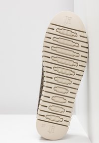 Suola di una scarpa, con una base in gomma beige testurizzata, dotata di scanalature e rilievi orizzontali, contrassegnata con "37" e "JH" sul tallone.