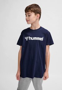 Mørkeblå bomulds t-shirt med korte ærmer, med et stort hvidt "hummel"-logo foran. Klassisk rund halsudskæring.