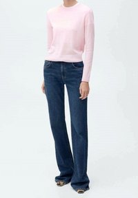 Helles rosa, langärmliges Sweatshirt mit geripptem Saum, kombiniert mit dunkelblauen, high-waisted, weiten Jeans, die über vordere Taschen und eine auffällige Naht verfügen.