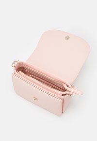 Růžová syntetická kožená křížová taška s překlopným klopným víkem, zlatými kovovými prvky, dvěma zipovými přihrádkami a hladkým povrchem.