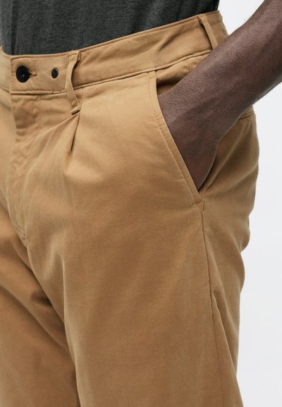 Khaki dress pants in cotton blend, featuring a flat front, side pockets, and button closure. Smooth texture with a fitted shape.
