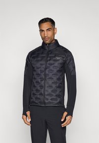 Μαύρο τζάκετ puffer με ραφές και ψηλό γιακά, διαθέτει κλείσιμο με φερμουάρ μπροστά και λογότυπο στη θήκη. Μακριά μανίκια από αντίθετο ύφασμα.