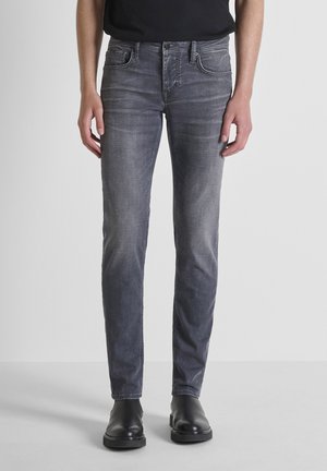 Gray denim jeans with a slim fit, featuring five pockets and a subtle fade detail. Worn with black ankle boots.