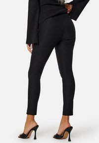 Zwarte legging met een aansluitend ontwerp, een gladde textuur en een cropped lengte, gecombineerd met open teen enkellaarsjes.