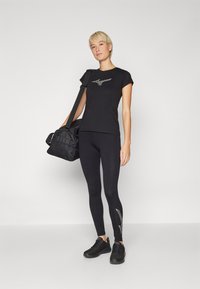 Svart treningst-skjorte med korte ermer og sølvlogo, sammen med svart tights med en subtil mønsterdetalj. Inkluderer en svart treningsbag.