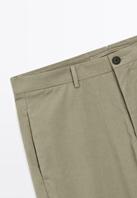 Kaki byxor med rak framdel, enkel knappstängning och bälteshällor. Slät textur med subtila sömnadsdetaljer; rak passform.