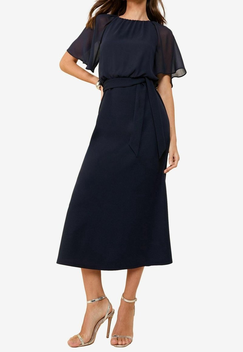Navy blue dress with sheer short sleeves, a fitted bodice, and a flowing skirt. Includes a fabric belt tied at the waist.