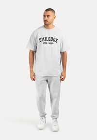 Conjunto de ropa deportiva de algodón gris que incluye una camiseta de manga corta con la impresión "SMILODOX ATHL. WEAR" en negro y pantalones de chándal a juego.