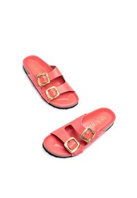 Chanclas de coral con dos correas anchas, hebillas cuadradas doradas y una textura suave. La suela negra proporciona contraste y mejora la durabilidad.