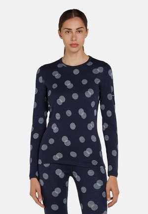 Navy blauw langemouwen top met grote, lichtgrijze stippen. Zachte stof met een gladde textuur, ronde halslijn en een slim fit ontwerp.