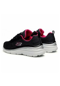 Scarpe sportive in rete nera con dettagli rosa e una spessa suola bianca. Presentano una tomaia testurizzata e un dettaglio del logo metallico sul lato.