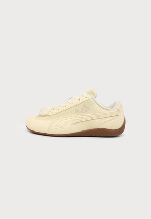 Cremefarbener Puma-Sneaker mit brauner Sohle, klassischem Seitenstreifen und Schnürverschluss, von der Außenseite vor einfarbigem Hintergrund gezeigt.