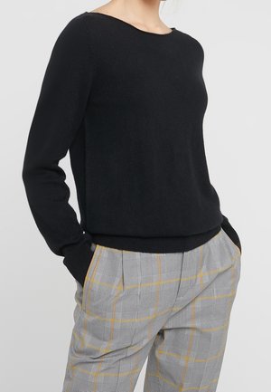 Pull en tricot noir avec un col rond et des manches longues. Associe à un pantalon à carreaux gris avec des accents jaunes et une coupe décontractée.