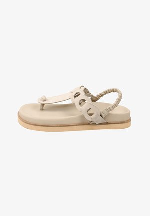 Beige flad sandal med polstret sål, rem rundt om tåen, dekorative cirkulære udskæringer på siden og elastisk slingback-rem.