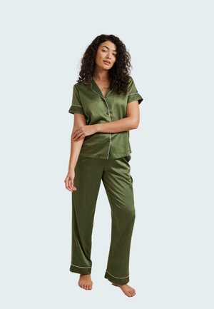 Conjunto de pijama de satén verde oliva con mangas cortas y pantalones, con ribetes blancos a lo largo de los bordes y un ajuste relajado. Textura suave.