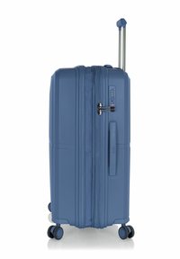 Valigia rigida blu con superficie texture, dotata di lucchetto combinato, manico estensibile e quattro ruote per una facile mobilità.