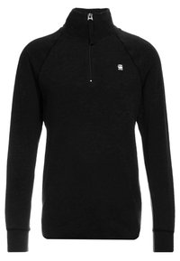 Svart kvartdraget pullover med långa raglanärmar, tillverkad av strukturerad tyg, har en liten logotyp på bröstet och elastiska muddar.