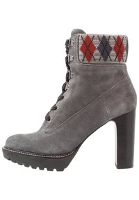 Botte de cheville en daim gris avec un talon haut épais, dotée d'un revers en tricot à motif argyle rouge, gris et blanc. Fermeture à lacets à l'avant.