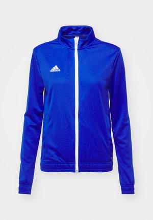 Blå atletisk jakke laget av glatt stoff, med høy krage, hel glidelås foran og hvit Adidas-logo på venstre bryst.