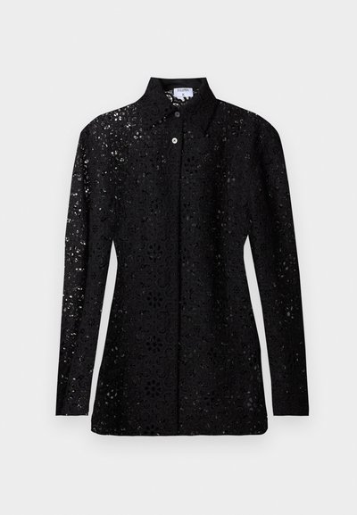 Blouse noire en dentelle à manches longues avec motif floral découpé, boutonnée sur le devant, avec col pointu, présentée sur fond uni.
