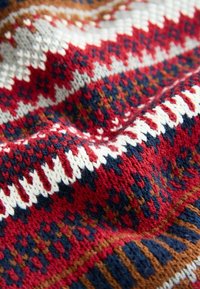 Nahaufnahme eines gestrickten Stoffs mit roten, marineblauen, weißen, grauen und braunen geometrischen Mustern sowie strukturierten Stichdetails.