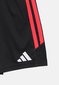 Černé sportovní šortky s červenými bočními pruhy, s bílým logem. Vyrobeno z lehkého, hladkého materiálu.