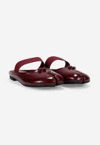 Zapatos de charol burdeos tipo slingback con un diseño curvado, abertura frontal, banda elástica y nudos decorativos en la parte superior. Suela plana.