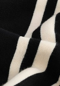 Tissu rayé noir et ivoire, avec une texture douce et des rayures larges et étroites alternées, le tout avec une finition lisse.