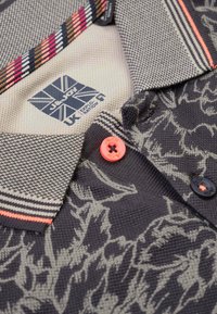 Polo shirt met kraag, versierd met een donker bloemenpatroon, van gebreide stof met textuur, met een contrasterende gestreepte kraag en koralen en zwarte knopen.