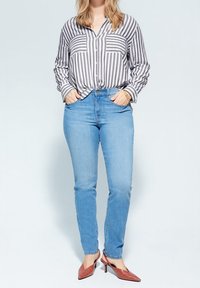 Stribet grå og hvid skjorte med knapper, lyseblå skinny jeans og røde hæle. Casual outfit med lange ærmer og to brystlommer.