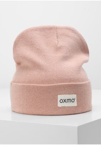 Berretto lavorato a maglia in un delicato rosa, con risvolto e un'etichetta tessuta con "oxmo" di lato. Texture liscia, forma arrotondata.