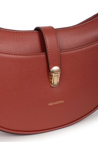 Strukturalna torba z teksturowanej burgundowej skóry o zaokrąglonym kształcie, z złotą klamrą i wytłoczonym logo "HEXAGONA" z przodu.