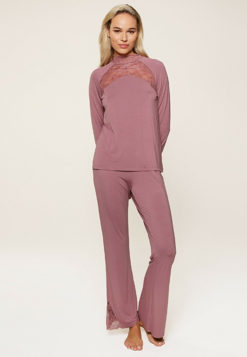 Ensemble de loungewear deux pièces en mauve, comprenant un haut à manches longues avec des bordures en dentelle et un pantalon assorti avec des accents en dentelle au bas. Texture lisse.