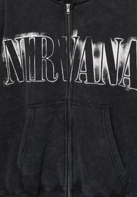 Schwarzer Kapuzenpullover mit Reißverschluss und großem "NIRVANA"-Aufdruck in weißen Buchstaben. Verfügt über eine weiche Textur und Fronttaschen.