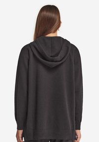 Dunkelgrauer Hoodie aus einem weichen, strukturierten Stoff. Verfügt über eine Kapuze mit Kordelzug, gerippte Bündchen, einen lockeren Schnitt und seitliche Schlitze am Saum.