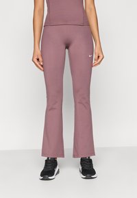 Φαρδιά αθλητικά παντελόνια από μαλακό μωβ ύφασμα με λεία υφή, που διαθέτουν το λευκό λογότυπο της Nike μπροστά και εφαρμοστό μέσο.