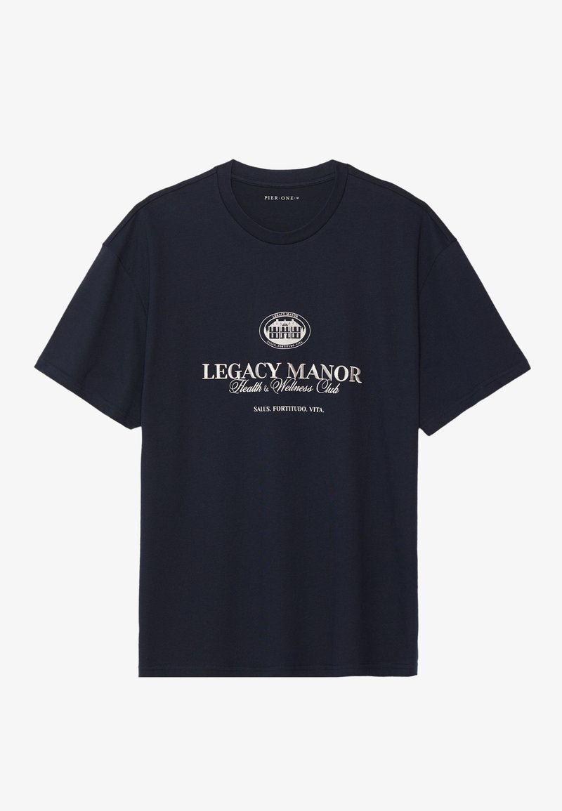 Tumed sinine puuvillane T-särk ümarate soontega kaeluses, lühikeste varrukatega ja keskel graafika, millel on "Legacy Manor" beežis kirjas.