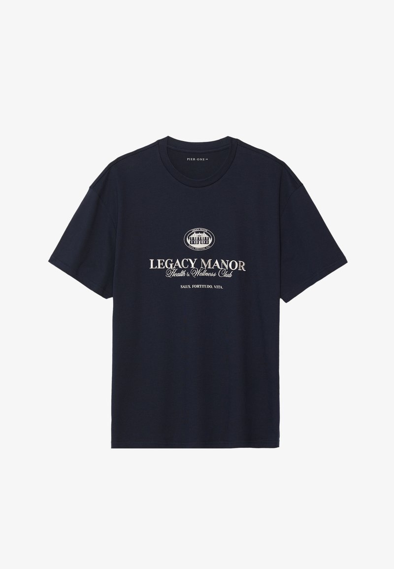 Tumed sinine puuvillane T-särk ümarate soontega kaeluses, lühikeste varrukatega ja keskel graafika, millel on "Legacy Manor" beežis kirjas.