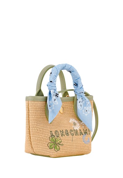 Woven tote bag with green trim, "LONGCHAMP" embroidery, floral designs, and a blue patterned scarf tied around one handle.