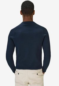 Mörkblå långärmad tröja, ribbad textur, rundad halsringning och figursydd design, med sömlösa axlar och avslappnad passform vid midjan.