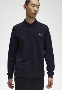 Tumedast sinise värviga puuvillane pikkade varrukatega polo särk, millel on kolme nupuga kaelus ja vasakul rinnal tikandiga logo. Sile tekstuur.