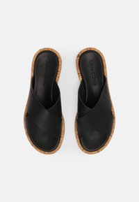 Sandales à glissière en cuir noir avec une semelle en liège. Présentent un design de lanières entrecroisées, une texture lisse et un branding gaufré sur la semelle intérieure.